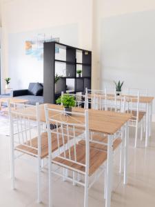 une salle à manger avec des tables en bois et des chaises blanches dans l'établissement Hatyai Humble Home 03, à Hat Yai