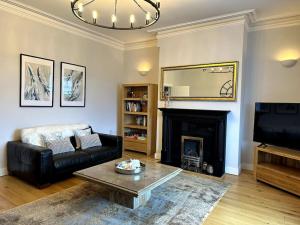 a living room with a black leather couch and a fireplace at Seaview Penthouse in Seaham