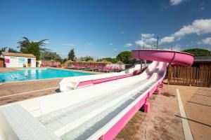 une piscine avec toboggan rose et blanc dans l'établissement Camping Saint-Nazaire, à Saint-Nazaire