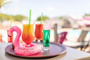- un plateau avec deux boissons et un flamingo rose sur une table dans l'établissement Camping Saint-Nazaire, à Saint-Nazaire