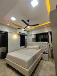 um quarto com uma cama branca e uma ventoinha de tecto em Cozy Furnished Apartment One Block From The Ocean em Mumbai