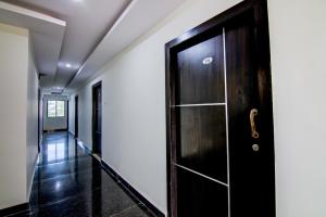 a hallway with a black door and white walls at Super Collection O Ramachandra Residency in Kurmannapalem