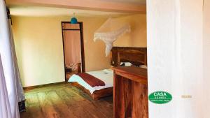 Bamasaba Community Lodge في Mbale: غرفة نوم بسرير ومكتب خشبي