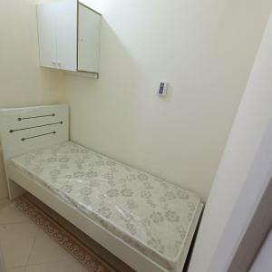 Al Basam Center في دبي: سرير في غرفة بجدار أبيض