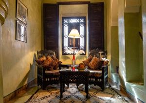 Dar Les Cigognes في مراكش: غرفة بها كرسيين وطاولة ومرآة