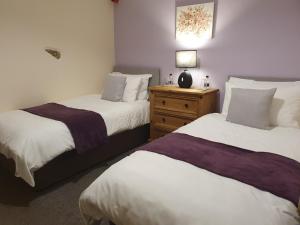 a bedroom with two beds and a table with a lamp at The Herdwick Inn in Penruddock