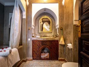 a bathroom with a fireplace with a sink and a mirror at Dar Les Cigognes in Marrakesh