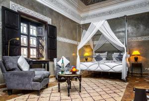Dar Les Cigognes في مراكش: غرفة نوم بسرير وكرسي وطاولة