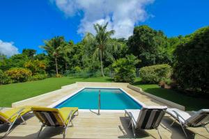 a swimming pool with three chairs and a yard at Five-Bedroom House in Saint Peter