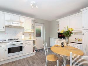 a kitchen with white cabinets and a table with a vase of flowers at Bluebell House in Bishop Auckland