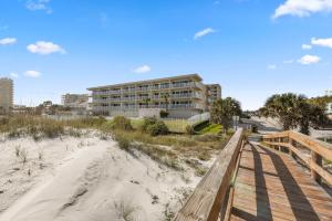 a building on the beach with a wooden boardwalk at Beachdrifter 406 in Jacksonville Beach
