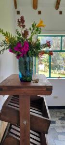 a vase of flowers sitting on a wooden table at Sauka Casa de campo in Villa de Leyva