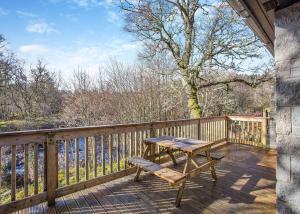 a wooden deck with a wooden table and a bench at Wildside Highland Lodges in Whitebridge