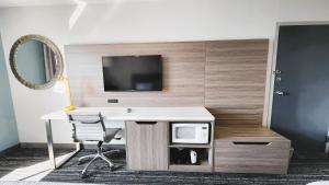 a desk with a chair and a tv on a wall at Americas Best Value Inn & Suites-Foley in Foley