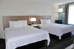 two beds in a hotel room with white sheets at Americas Best Value Inn & Suites-Foley in Foley