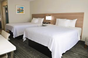 two beds in a hotel room with white sheets at Americas Best Value Inn & Suites-Foley in Foley