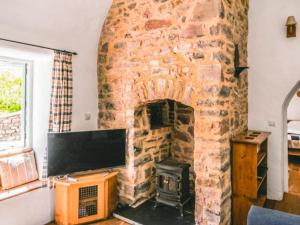 a stone fireplace in a living room with a flat screen tv at Shute Cottage in Manorbier