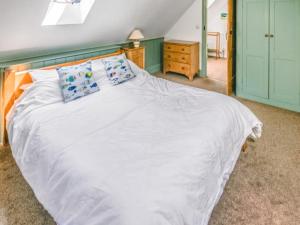 a bedroom with a white bed with blue pillows at Shute Cottage in Manorbier