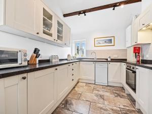 a kitchen with white cabinets and a tile floor at The Cottage in South Barrow