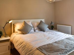 een slaapkamer met een groot bed met kussens bij Bramble Cottage in Bramham