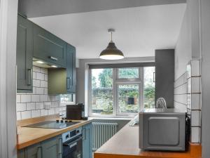 a kitchen with blue cabinets and a tv on a counter at Bramble Cottage in Bramham