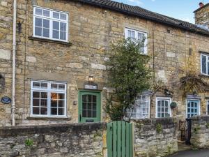 an old stone house with a green door at Bramble Cottage in Bramham