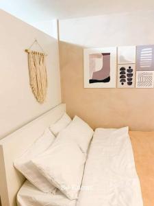 Bett mit weißen Kissen in einem Zimmer in der Unterkunft Korean Themed Condo Staycation in Marilao, Bulacan in Marilao