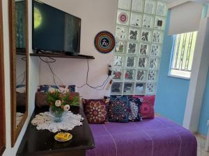 a living room with a tv and a table with a purple couch at Pertinho da Mata in Cachoeiras de Macacu