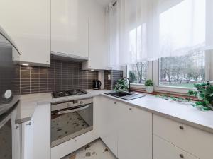 a kitchen with white cabinets and a stove top oven at Bonifraterska Papaya Apartment in Warsaw