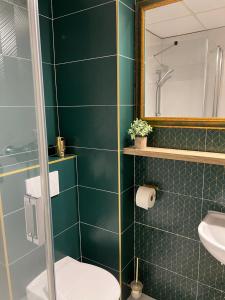 a bathroom with green tiled walls and a toilet and a mirror at Penzión Aira in Zvolen