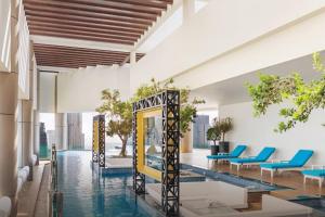 een hotellobby met een zwembad en blauwe stoelen bij Stunning 2br With Burj Views Infinity Pool in Dubai
