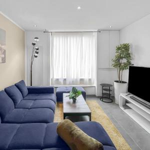 a living room with a blue couch and a tv at Escapade Authentique in Aubange