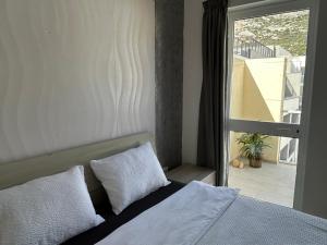 1 cama con 2 almohadas en una habitación con ventana en Arzella - spacious two bedroom apartments, en Xlendi