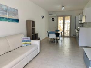 ein Wohnzimmer mit einem weißen Sofa und einer Küche in der Unterkunft Cala Bianca app 1 in SantʼAntìoco