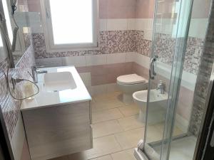 ein Bad mit einem WC, einem Waschbecken und einer Dusche in der Unterkunft Cala Bianca app 1 in SantʼAntìoco