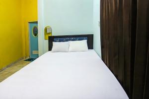 1 dormitorio con cama blanca y puerta de madera en Wisma Dhana Syariah en Praya