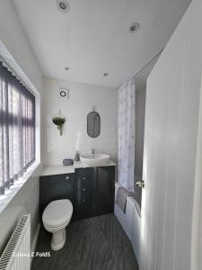 uma casa de banho branca com um WC e um lavatório em By the Joyous Stays em Stoke on Trent