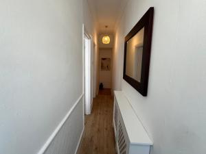 un couloir avec des murs blancs et une photo sur le mur dans l'établissement 2 Bedroom flat 10 min walk to tube, à Londres