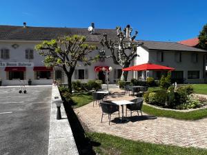 un patio avec des tables et des chaises en face d'un bâtiment dans l'établissement La Bonne Auberge, à Ségny