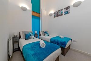 2 camas en una habitación de color azul y blanco en Stylish 2 bedroom apartment, 2 bathrooms, free parking for all guest, wifi, Sky, Netflix, walking distance to city centre, sleeps 5, outside patio space, ground floor en Milton Keynes