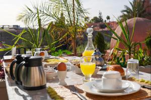 un tavolo con prodotti per la colazione e una bottiglia di succo d'arancia di Riad Roummana Marrakech a Marrakech