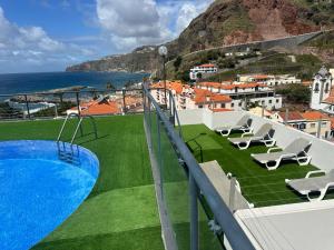 a balcony with a pool and chairs and the ocean at Flag Hotel Madeira - Ribeira Brava in Ribeira Brava