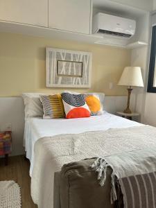um quarto com uma cama branca e almofadas coloridas em Is Liberdade em São Paulo