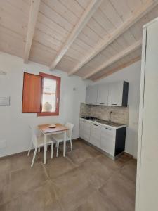 eine Küche mit einem Tisch, Stühlen und einem Waschbecken in der Unterkunft Villa Campidanese in Assemini