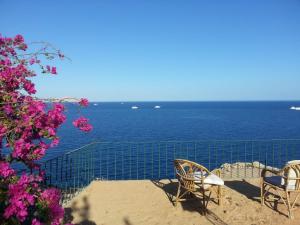 a view of the ocean with two chairs and a fence at Vacation villa in Sharm El Sheikh on the beach in Sharm El Sheikh