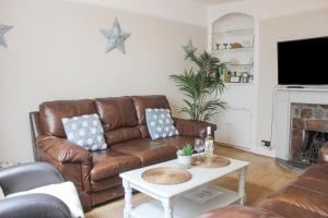 a living room with a brown leather couch and a table at Sandcastles 15A Fore Street in Salcombe
