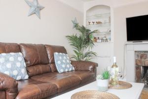 a living room with a brown leather couch at Sandcastles 15A Fore Street in Salcombe