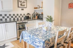 una cucina con tavolo e tovaglia blu e bianca di Sandcastles 15A Fore Street a Salcombe