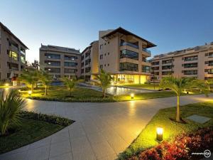 a courtyard with palm trees and buildings at night at EKOARA BEIRA MAR 127 in Porto De Galinhas