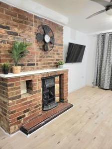a brick fireplace with a clock on a wall at Three Bed Flat In Mile End in London